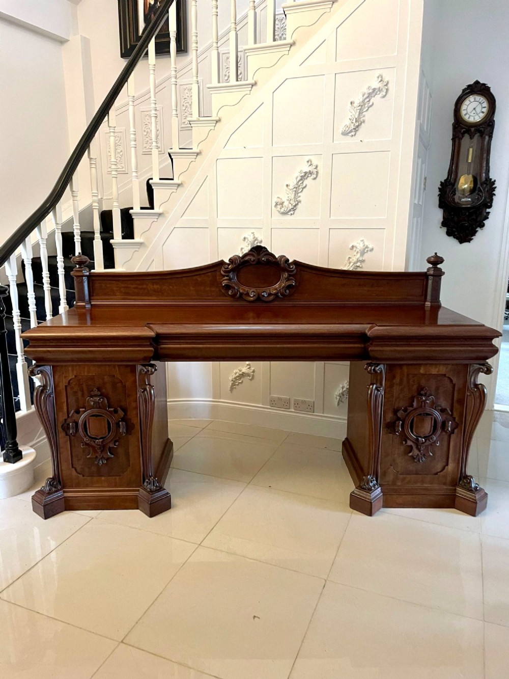 A large William IV mahogany sideboard featuring an ornate carved splashback upstand and two pedestal cupboards with carved scrollwork. View VI