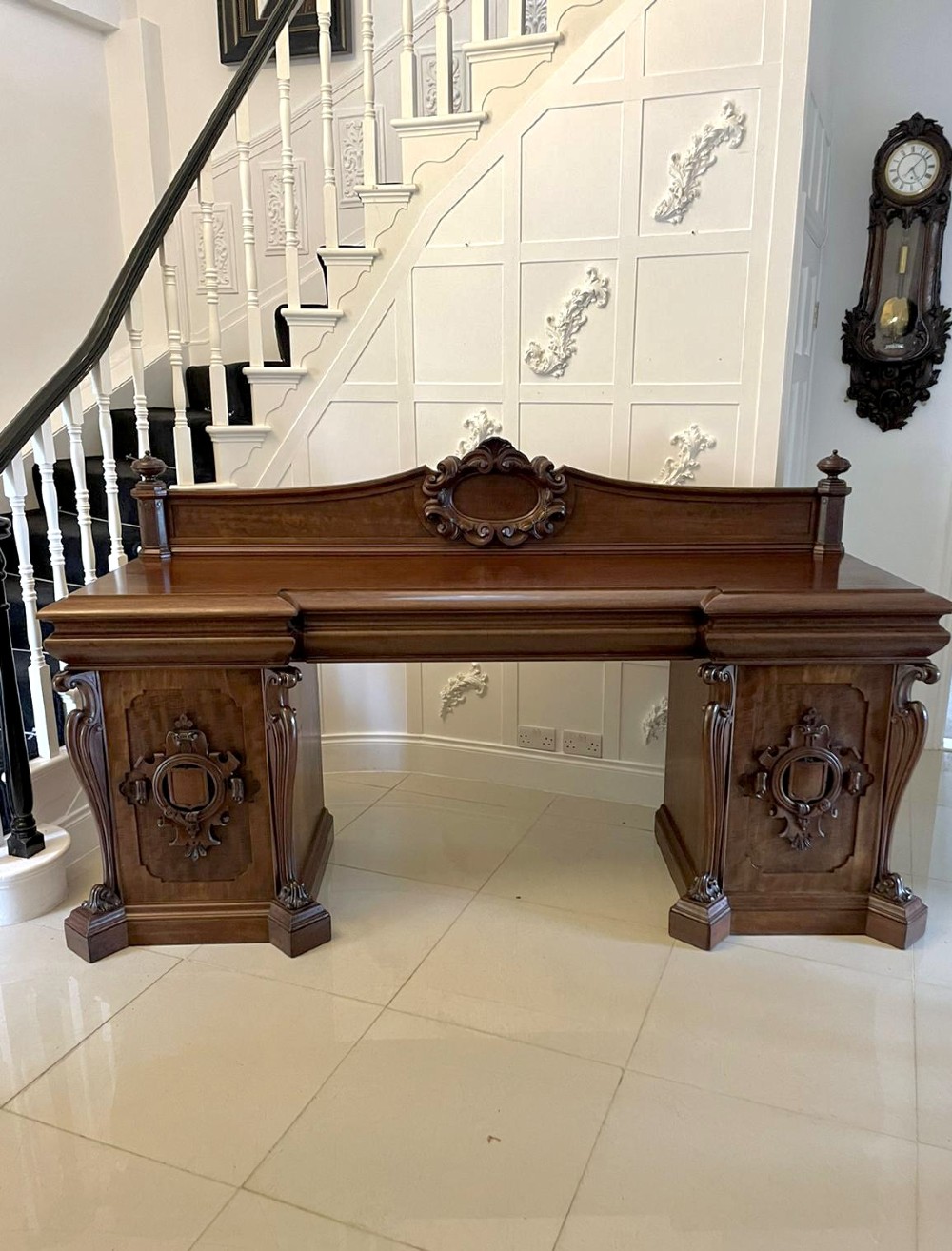 A large William IV mahogany sideboard featuring an ornate carved splashback upstand and two pedestal cupboards with carved scrollwork.