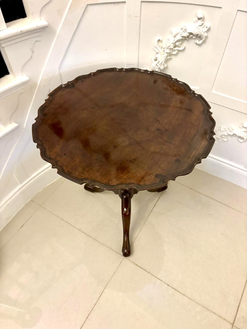 An 18th-century mahogany Chippendale tilt-top tripod table shown upright with a scalloped piecrust edge, turned column, and three cabriole legs. View IV