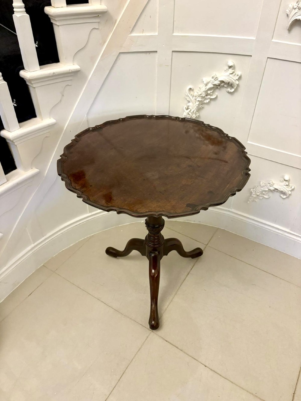 An 18th-century mahogany Chippendale tilt-top tripod table shown upright with a scalloped piecrust edge, turned column, and three cabriole legs. View X