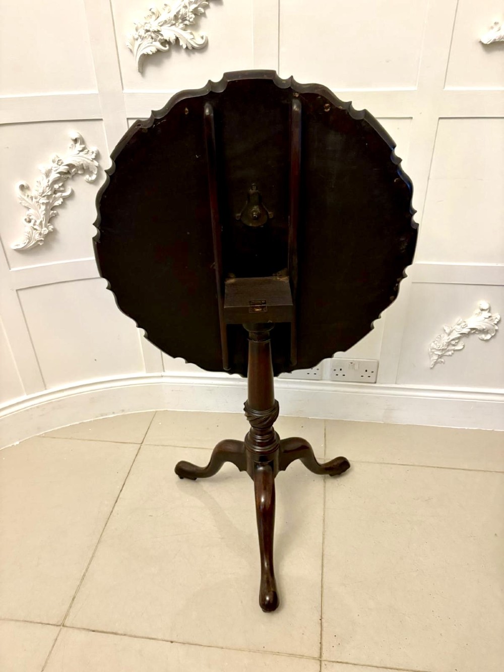 An 18th-century mahogany Chippendale tilt-top tripod table shown upright with a scalloped piecrust edge, turned column, and three cabriole legs. View XI