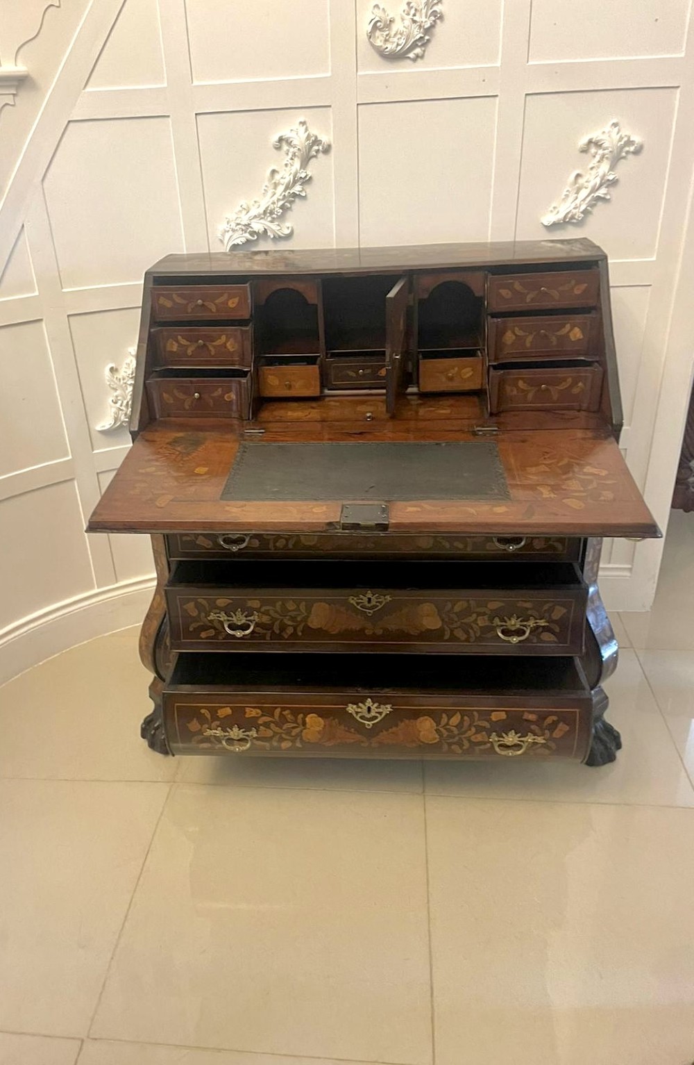 An 18th-century style mahogany bombe bureau featuring floral marquetry inlay across the slant front and drawers, complete with brass handles and carved claw feet. View V