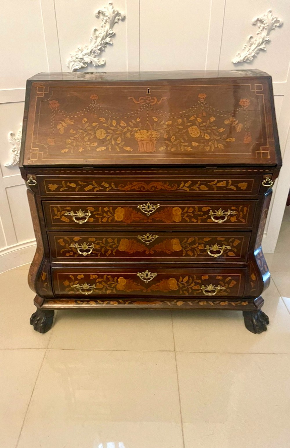 An 18th-century style mahogany bombe bureau featuring floral marquetry inlay across the slant front and drawers, complete with brass handles and carved claw feet.