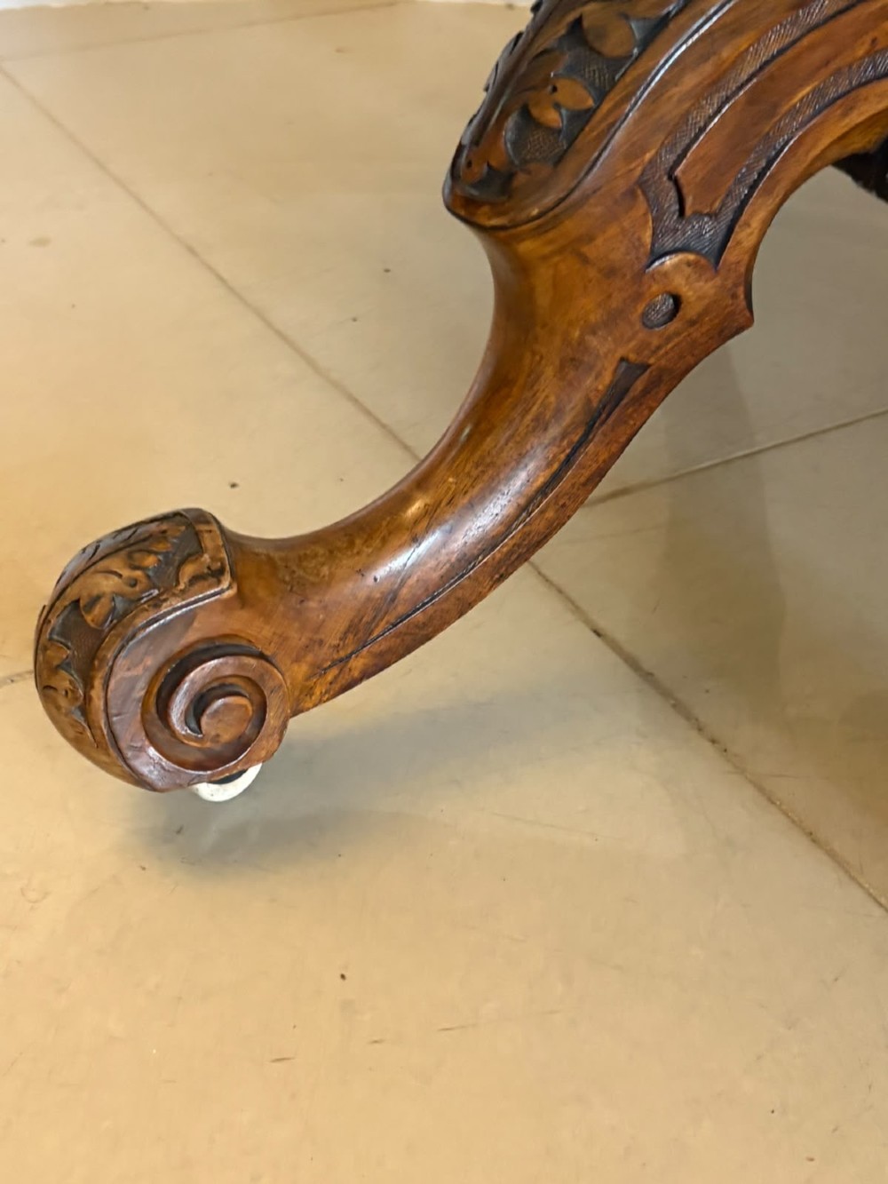 An antique Victorian oval tilt-top table made of burr walnut with a four-star carved pedestal base and white ceramic castors, shown with the tabletop tilted vertically. View VI