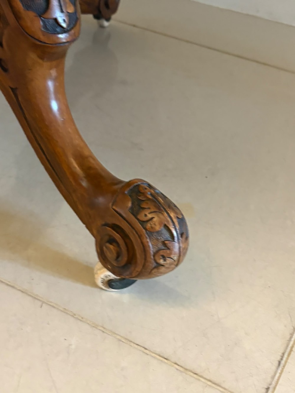 An antique Victorian oval tilt-top table made of burr walnut with a four-star carved pedestal base and white ceramic castors, shown with the tabletop tilted vertically. View VIII