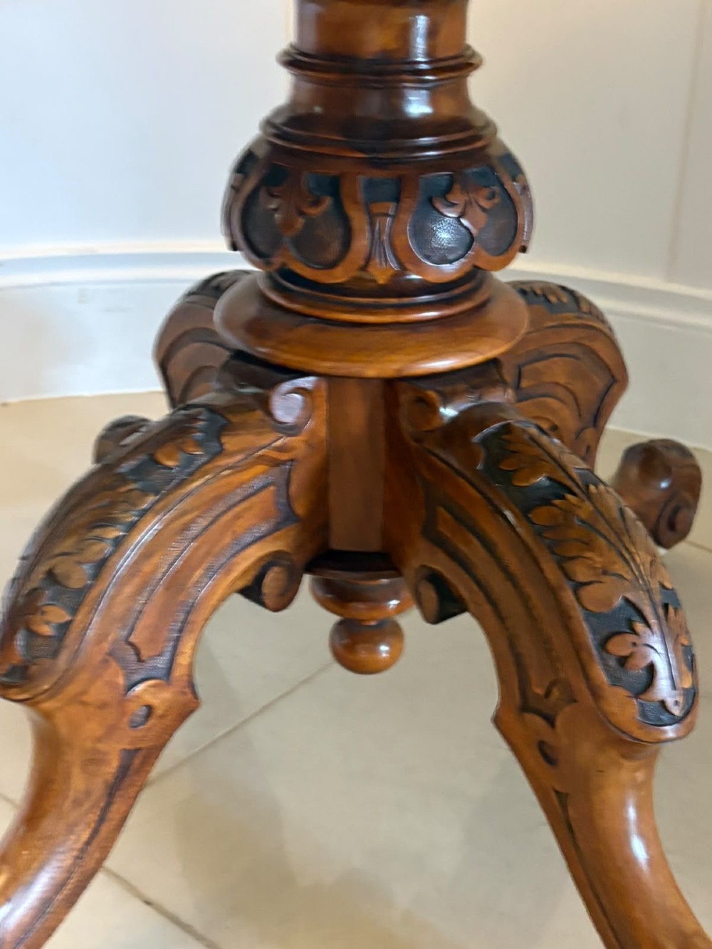An antique Victorian oval tilt-top table made of burr walnut with a four-star carved pedestal base and white ceramic castors, shown with the tabletop tilted vertically. View XIII