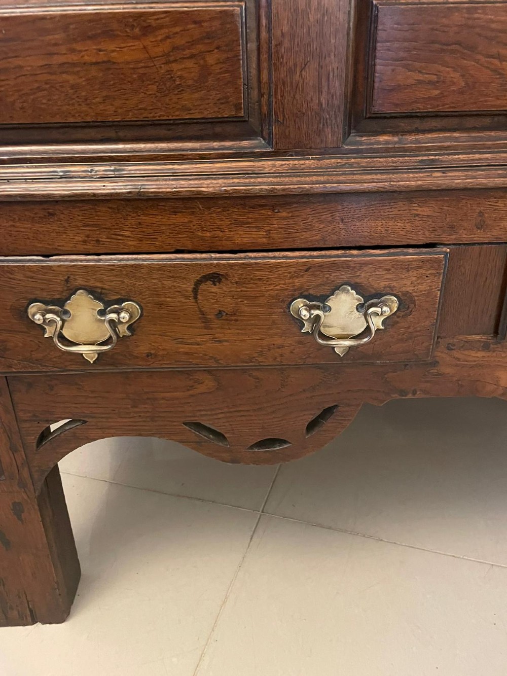 An 18th-century oak coffer elevated on a stand, with geometric panel moulding across the front lid section, lower brass-handled drawers, and square legs. View II