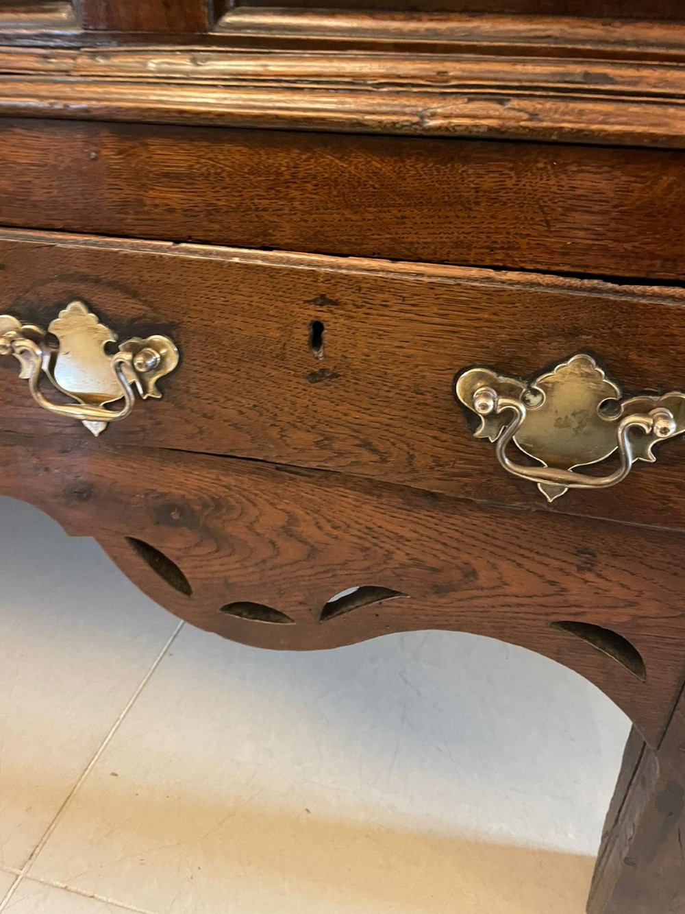 An 18th-century oak coffer elevated on a stand, with geometric panel moulding across the front lid section, lower brass-handled drawers, and square legs. View IV