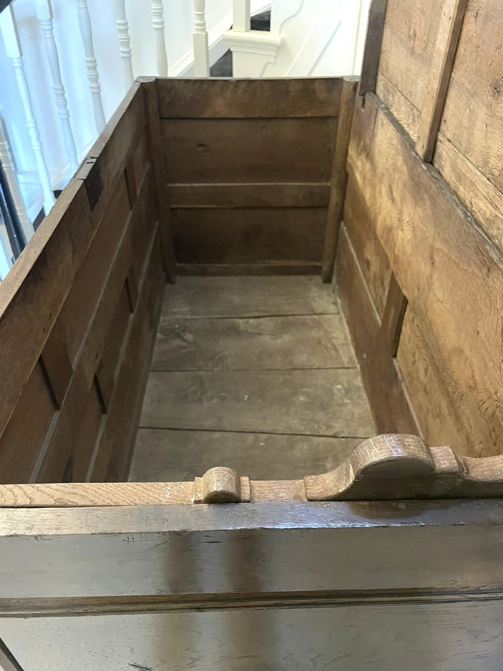 An 18th-century oak coffer elevated on a stand, with geometric panel moulding across the front lid section, lower brass-handled drawers, and square legs. View V