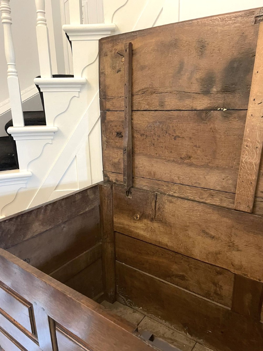 An 18th-century oak coffer elevated on a stand, with geometric panel moulding across the front lid section, lower brass-handled drawers, and square legs. View VI