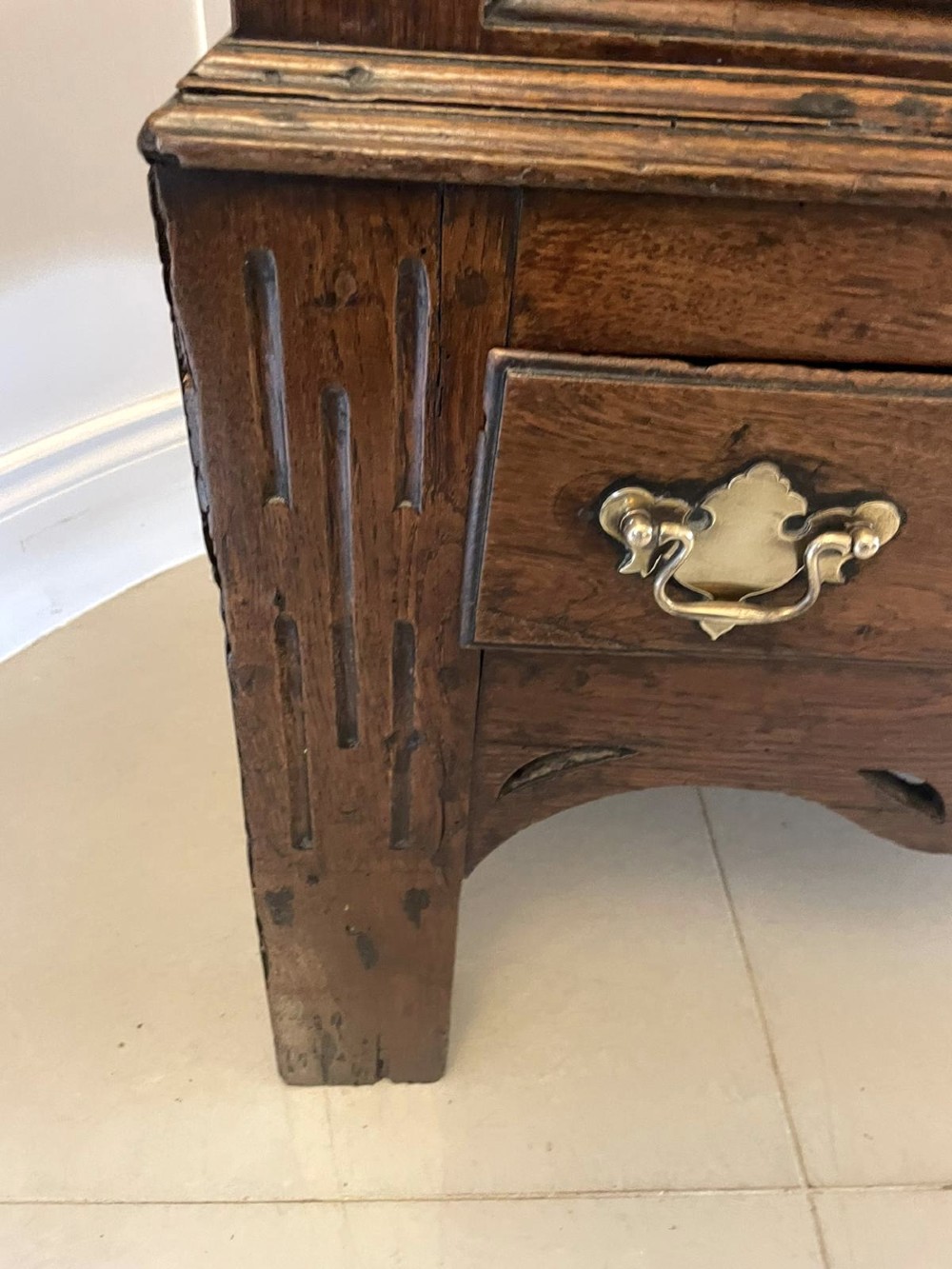 An 18th-century oak coffer elevated on a stand, with geometric panel moulding across the front lid section, lower brass-handled drawers, and square legs. View VIII