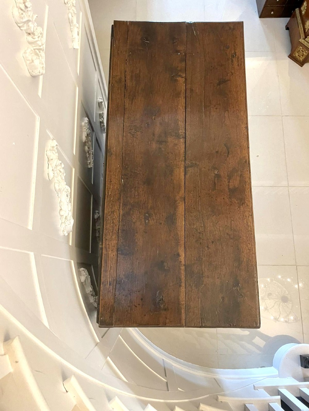 An 18th-century oak coffer elevated on a stand, with geometric panel moulding across the front lid section, lower brass-handled drawers, and square legs. View XI