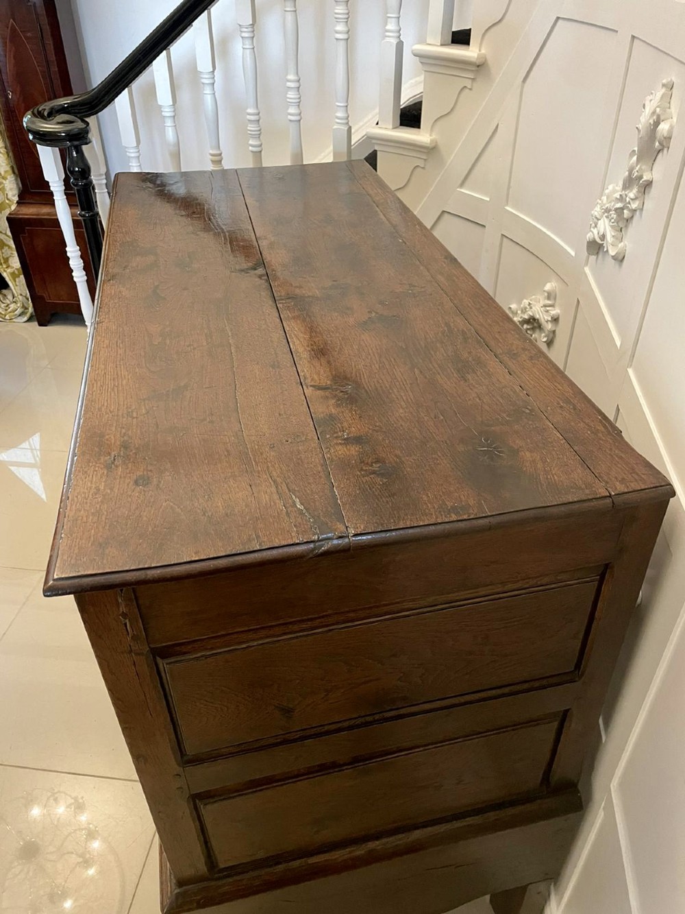 An 18th-century oak coffer elevated on a stand, with geometric panel moulding across the front lid section, lower brass-handled drawers, and square legs. View XIII