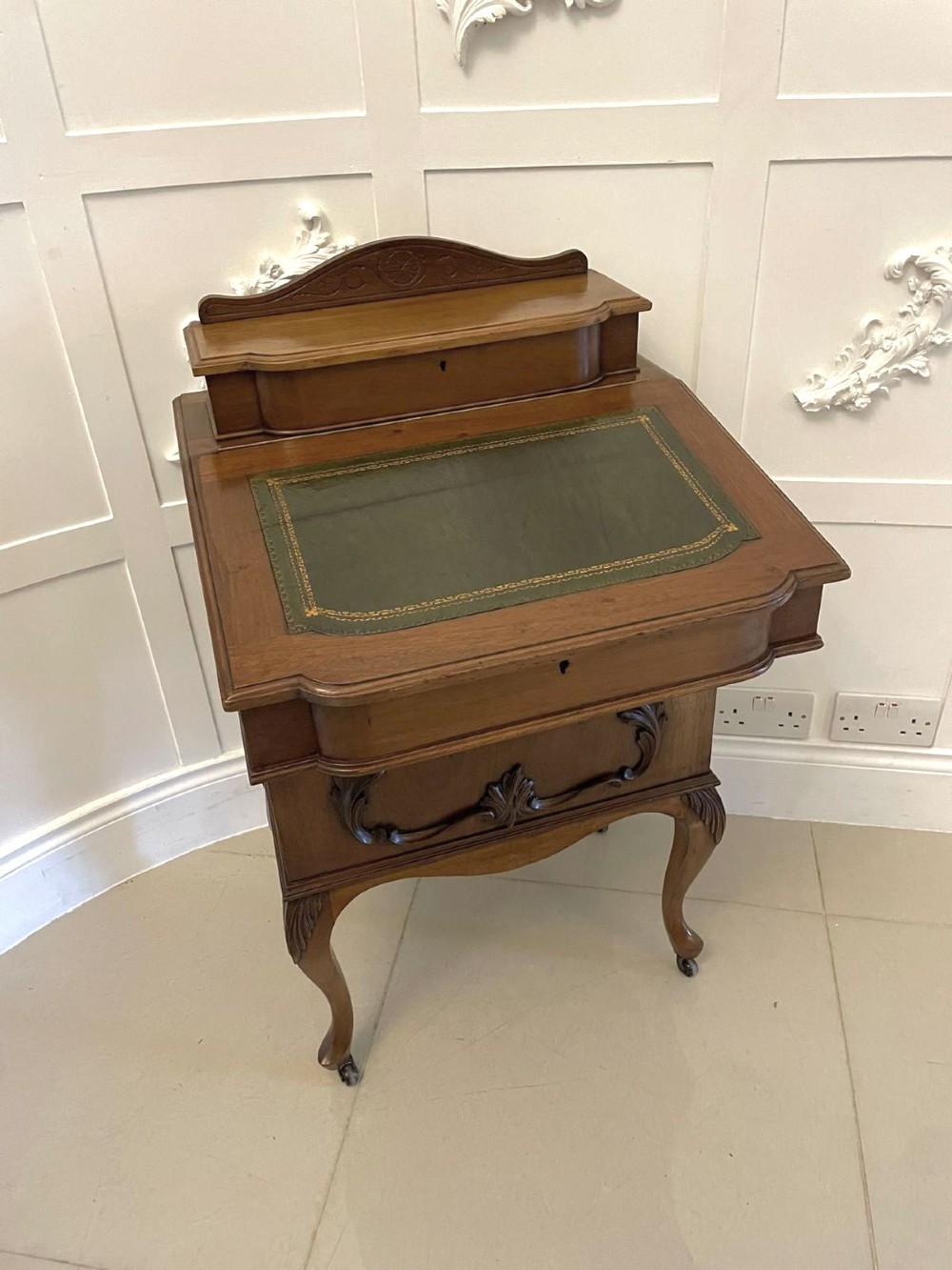A Victorian walnut Davenport desk featuring a green leather writing slope, an upper stationery box, and carved cabriole legs on castors.