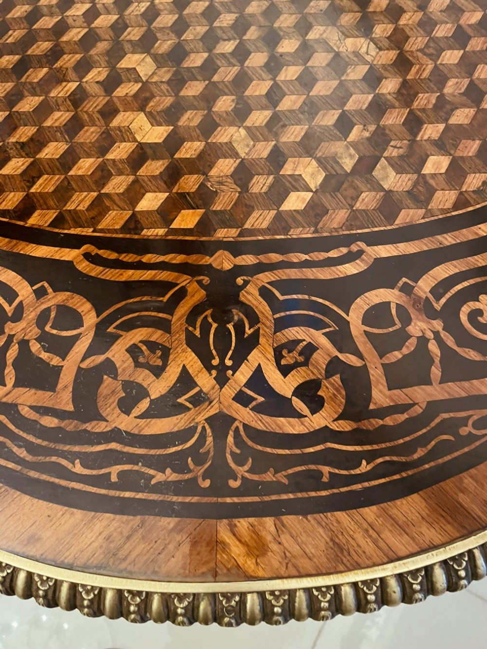 An antique French Rococo Revival centre table featuring detailed marquetry and parquetry wood patterns, serpentine edges, brass ormolu mounts, and curved cabriole legs. View VI