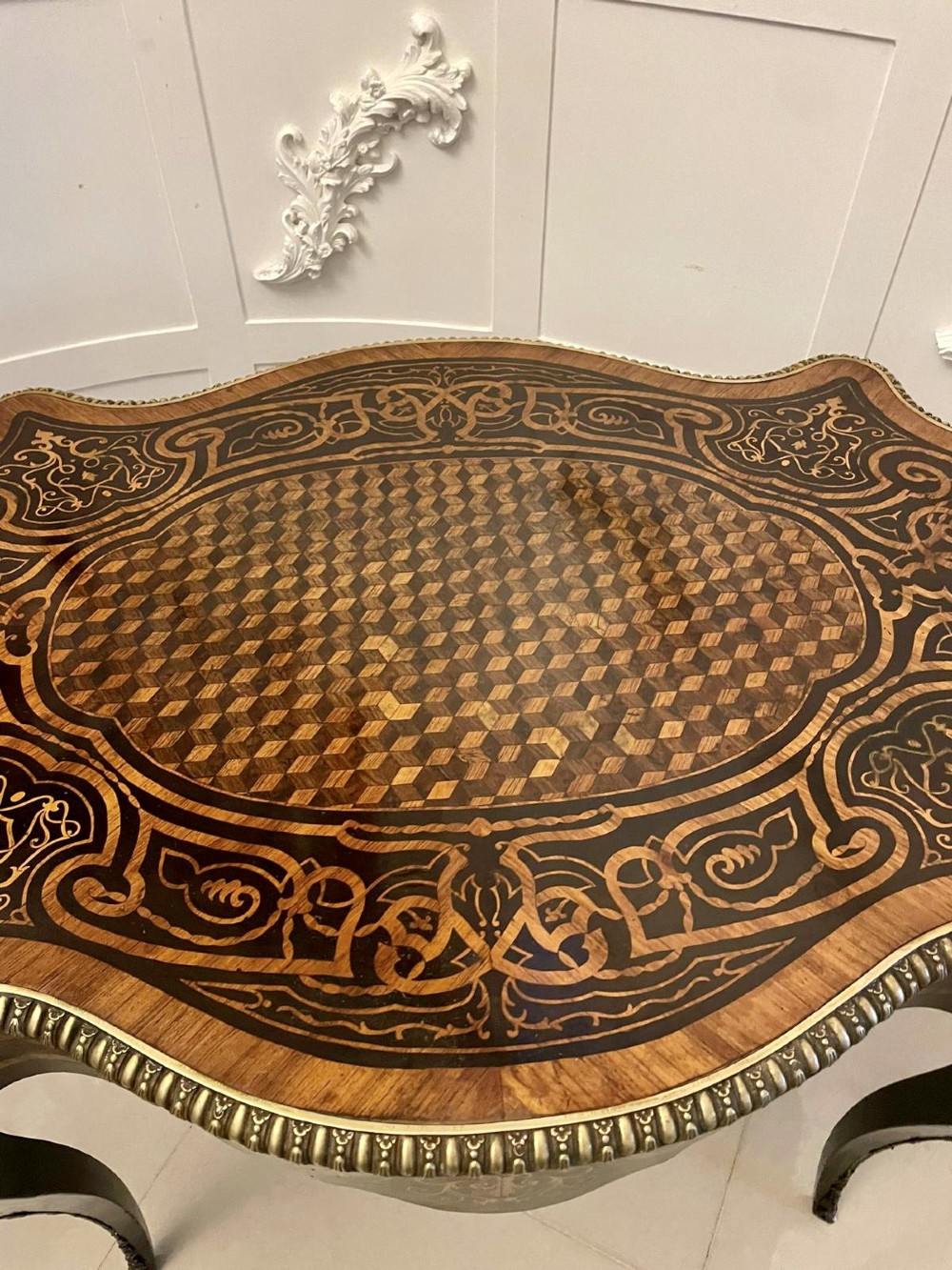 An antique French Rococo Revival centre table featuring detailed marquetry and parquetry wood patterns, serpentine edges, brass ormolu mounts, and curved cabriole legs. View VIII