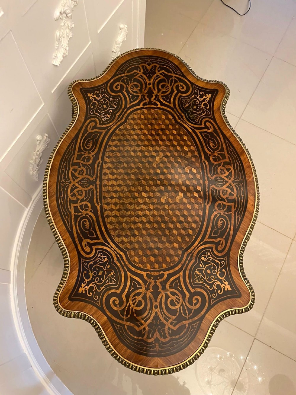 An antique French Rococo Revival centre table featuring detailed marquetry and parquetry wood patterns, serpentine edges, brass ormolu mounts, and curved cabriole legs. View IX