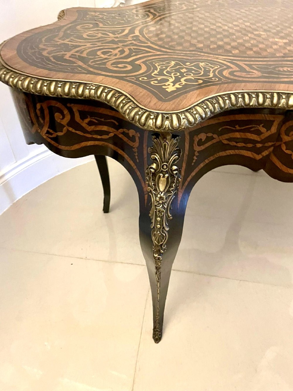 An antique French Rococo Revival centre table featuring detailed marquetry and parquetry wood patterns, serpentine edges, brass ormolu mounts, and curved cabriole legs. View XV
