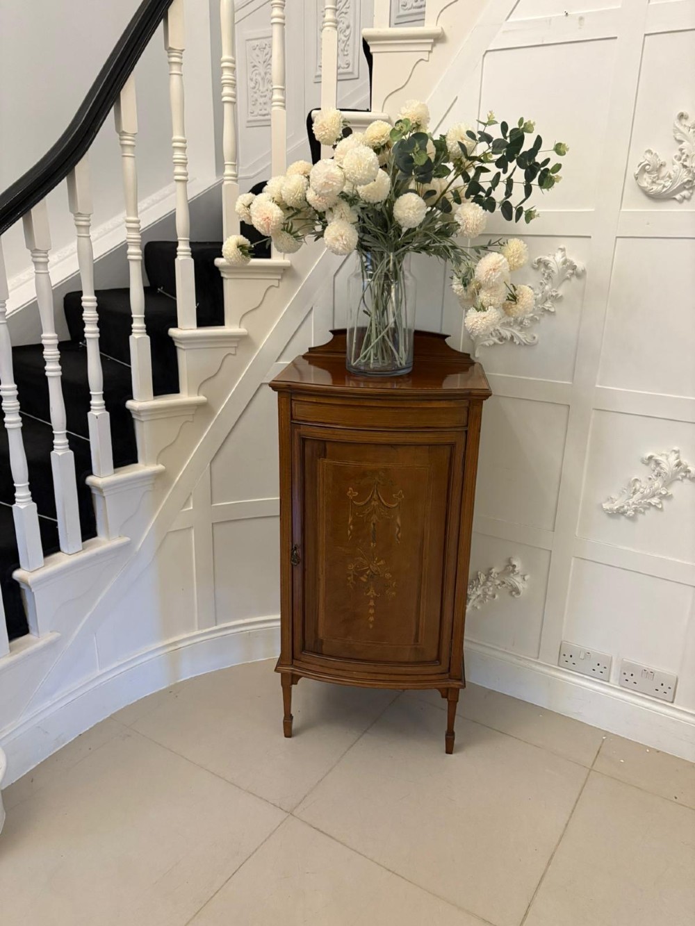 An Edwardian mahogany bow-fronted side cabinet featuring ribbon and urn marquetry inlay, a raised gallery back, and tapered square legs. View III