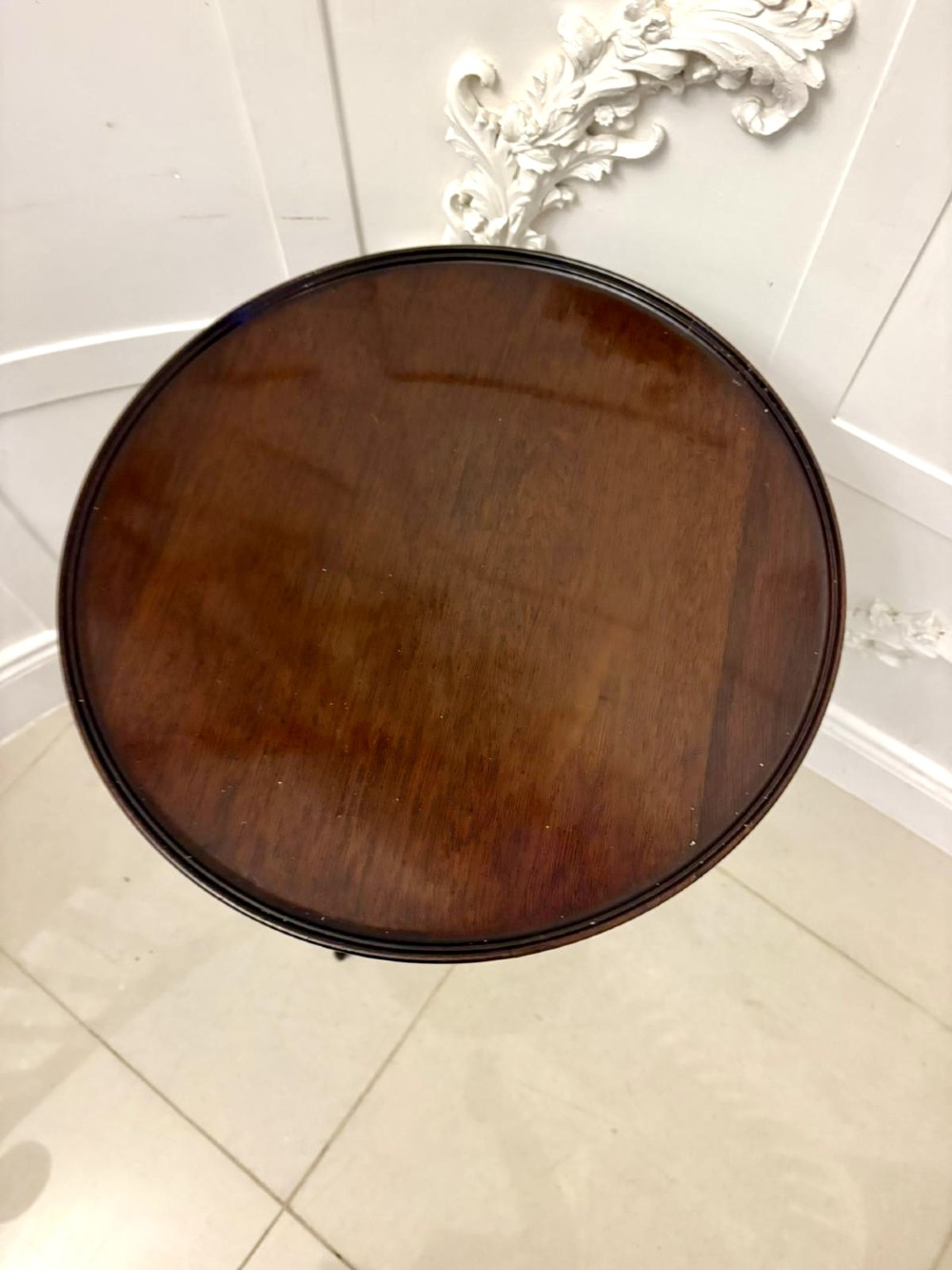 A circular dark mahogany tripod table featuring a moulded rim, turned baluster column, and three shaped legs. View II