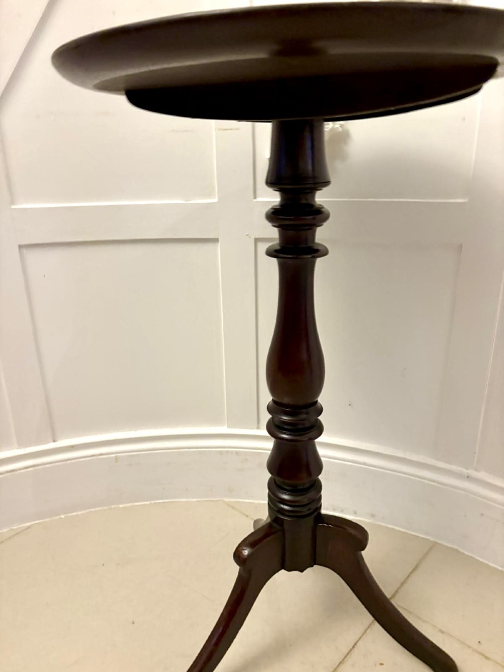 A circular dark mahogany tripod table featuring a moulded rim, turned baluster column, and three shaped legs. View V