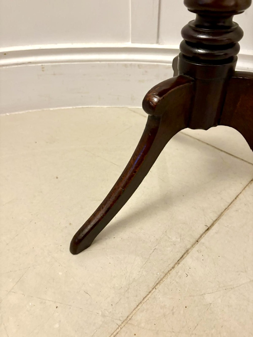 A circular dark mahogany tripod table featuring a moulded rim, turned baluster column, and three shaped legs. View VII
