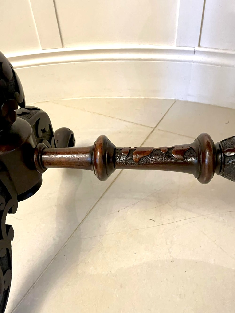 An antique Victorian oval centre table featuring a figured burr walnut top with moulded edges, carved end supports, a turned stretcher, and brass castors. View IV