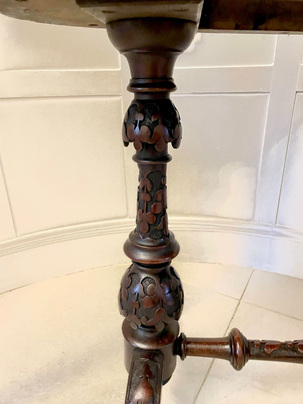 An antique Victorian oval centre table featuring a figured burr walnut top with moulded edges, carved end supports, a turned stretcher, and brass castors. View VI