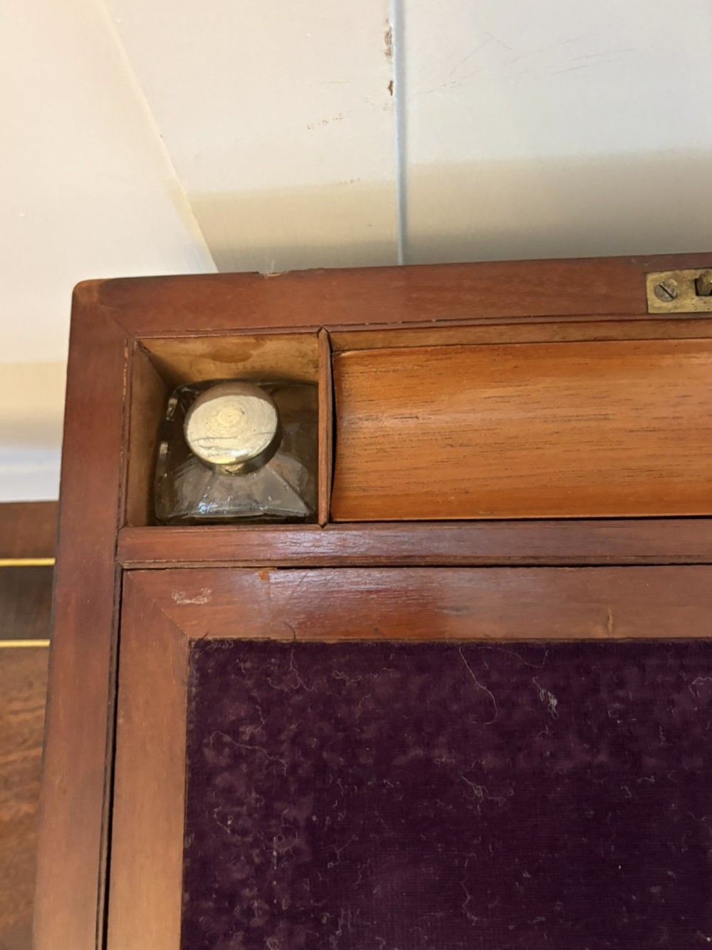 A rectangular Victorian mahogany writing box featuring brass corner brackets, vertical brass strapping, a central brass shield inlay, and a brass keyhole escutcheon. View VI