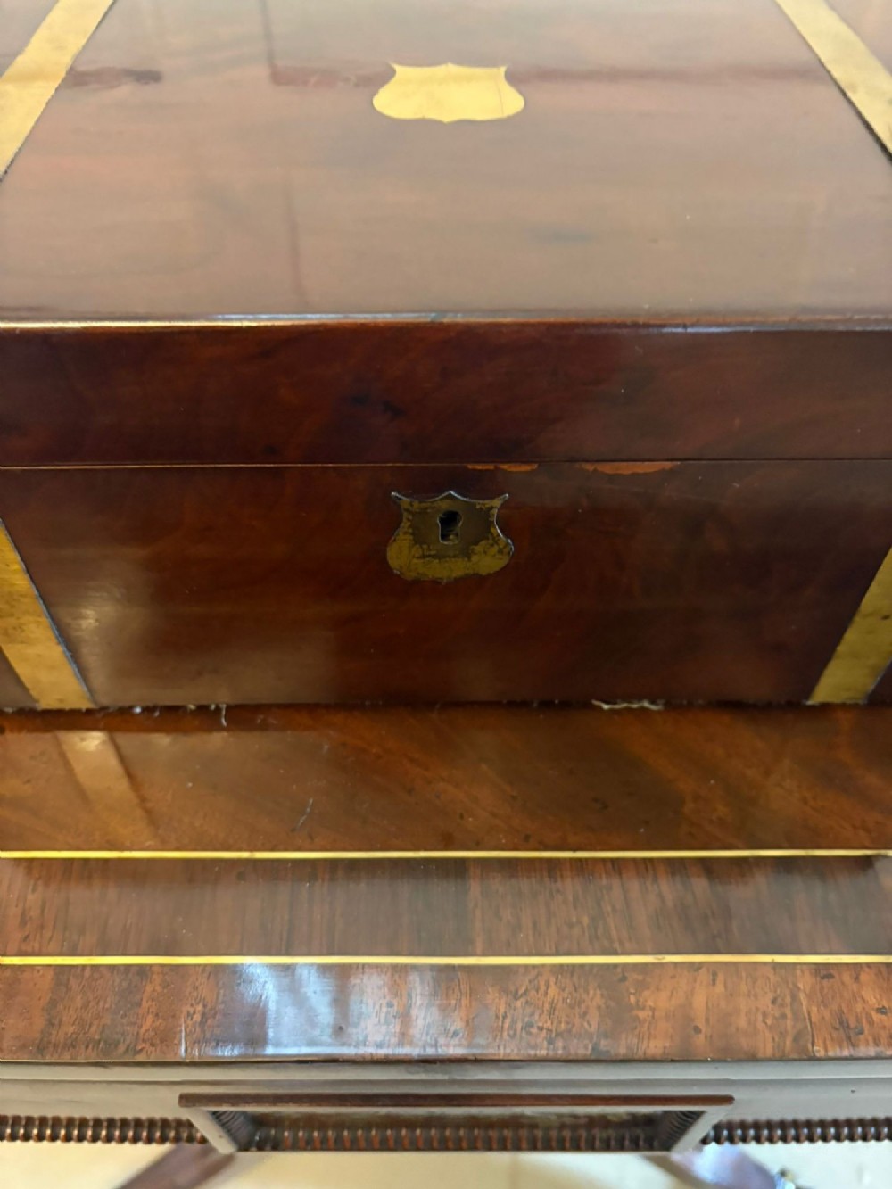 A rectangular Victorian mahogany writing box featuring brass corner brackets, vertical brass strapping, a central brass shield inlay, and a brass keyhole escutcheon. View VII
