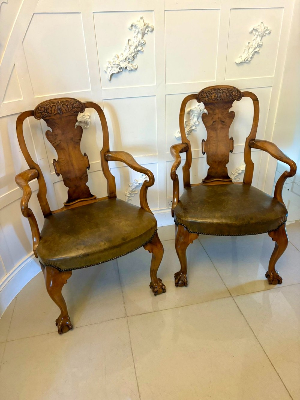 A pair of carved walnut desk armchairs featuring vasiform splats, green leather seats with brass studding, and cabriole legs ending in ball and claw feet. View XI