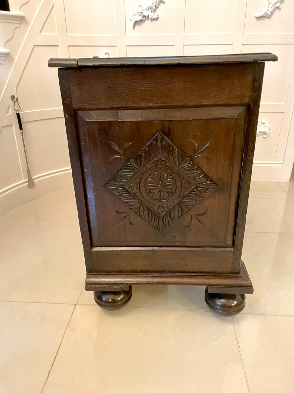 A dark carved oak coffer featuring three arcaded front panels, carved border details, top iron hinges, and turned bun feet. View XI