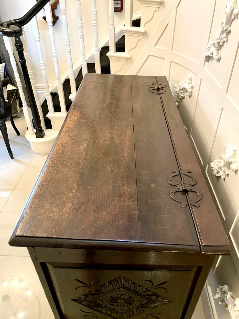 A dark carved oak coffer featuring three arcaded front panels, carved border details, top iron hinges, and turned bun feet. View XII