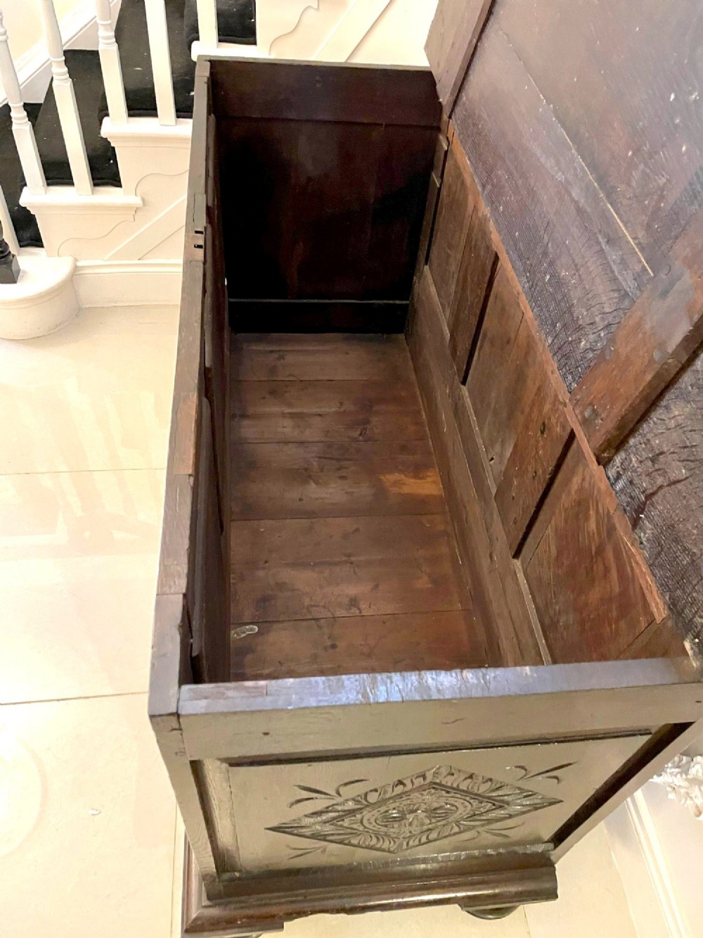 A dark carved oak coffer featuring three arcaded front panels, carved border details, top iron hinges, and turned bun feet. View XIII