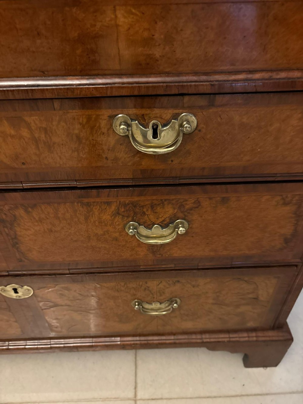 An 18th-century George I figured walnut bureau bookcase featuring two mirrored upper cabinet doors, a slant-front writing desk, and three lower drawers on bracket feet. View VII