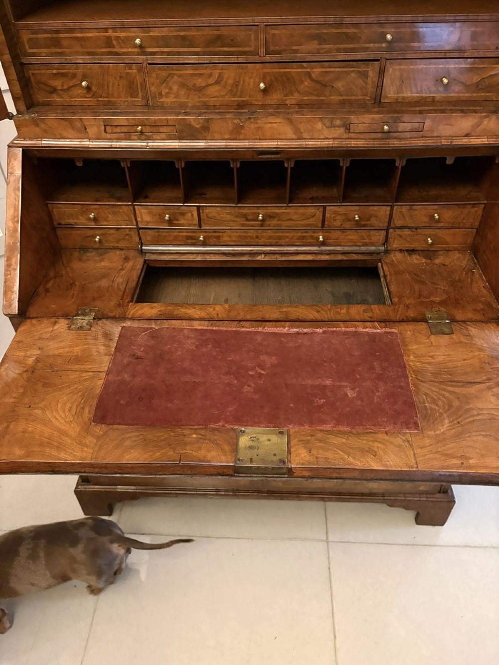 An 18th-century George I figured walnut bureau bookcase featuring two mirrored upper cabinet doors, a slant-front writing desk, and three lower drawers on bracket feet. View IX