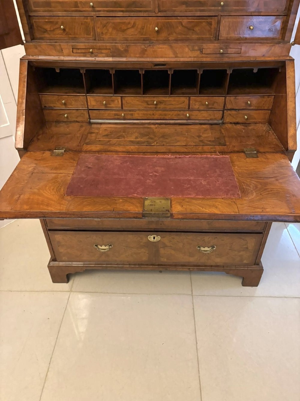 An 18th-century George I figured walnut bureau bookcase featuring two mirrored upper cabinet doors, a slant-front writing desk, and three lower drawers on bracket feet. View XI