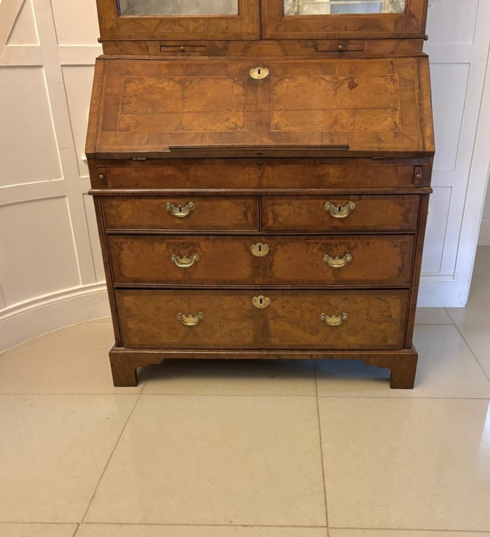 An 18th-century George I figured walnut bureau bookcase featuring two mirrored upper cabinet doors, a slant-front writing desk, and three lower drawers on bracket feet. View XIII