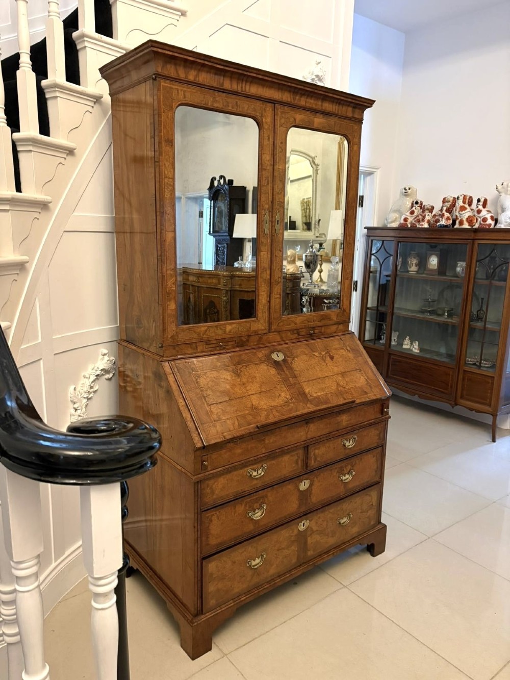 An 18th-century George I figured walnut bureau bookcase featuring two mirrored upper cabinet doors, a slant-front writing desk, and three lower drawers on bracket feet. View XIV