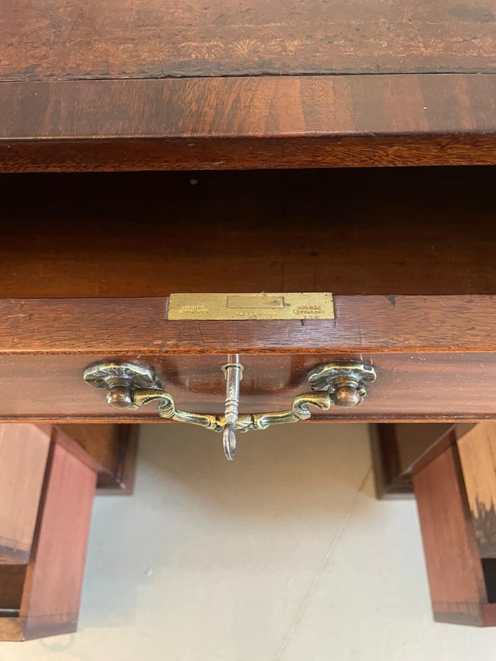 A Victorian mahogany freestanding kneehole desk featuring a leather writing insert, multiple drawers with brass handles, and side brass carrying handles. View II