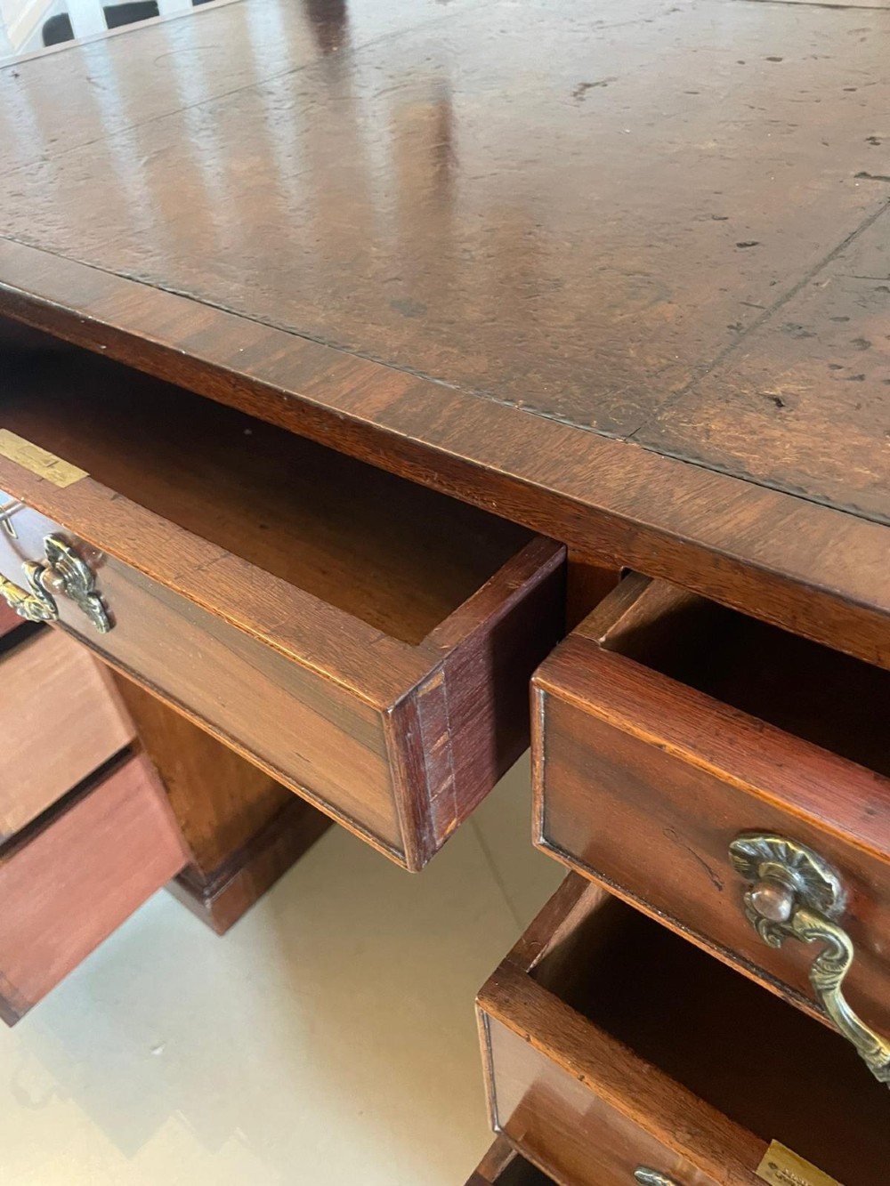A Victorian mahogany freestanding kneehole desk featuring a leather writing insert, multiple drawers with brass handles, and side brass carrying handles. View III