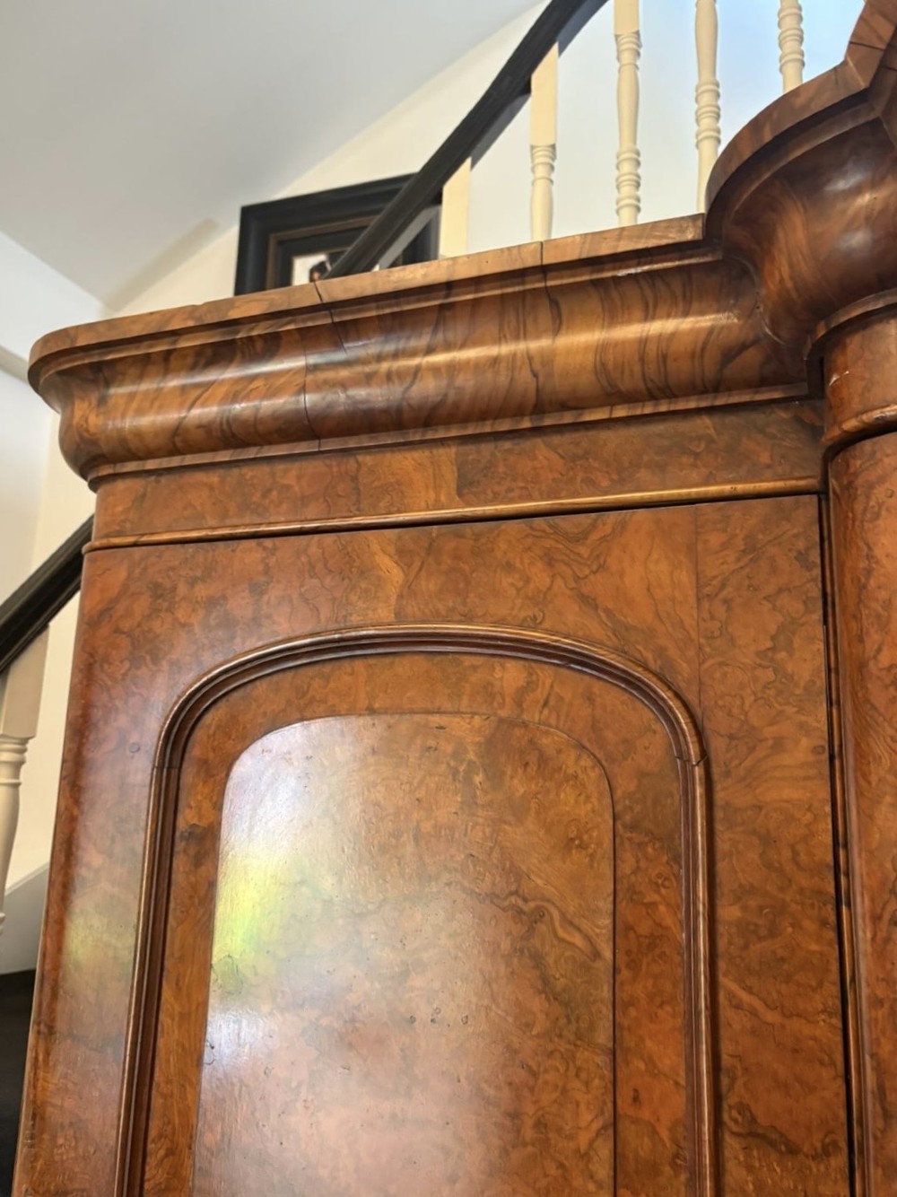 An antique Victorian burr walnut three-door wardrobe featuring an arched central mirrored door crowned with a carved crest, flanked by two burr walnut panelled doors. View III