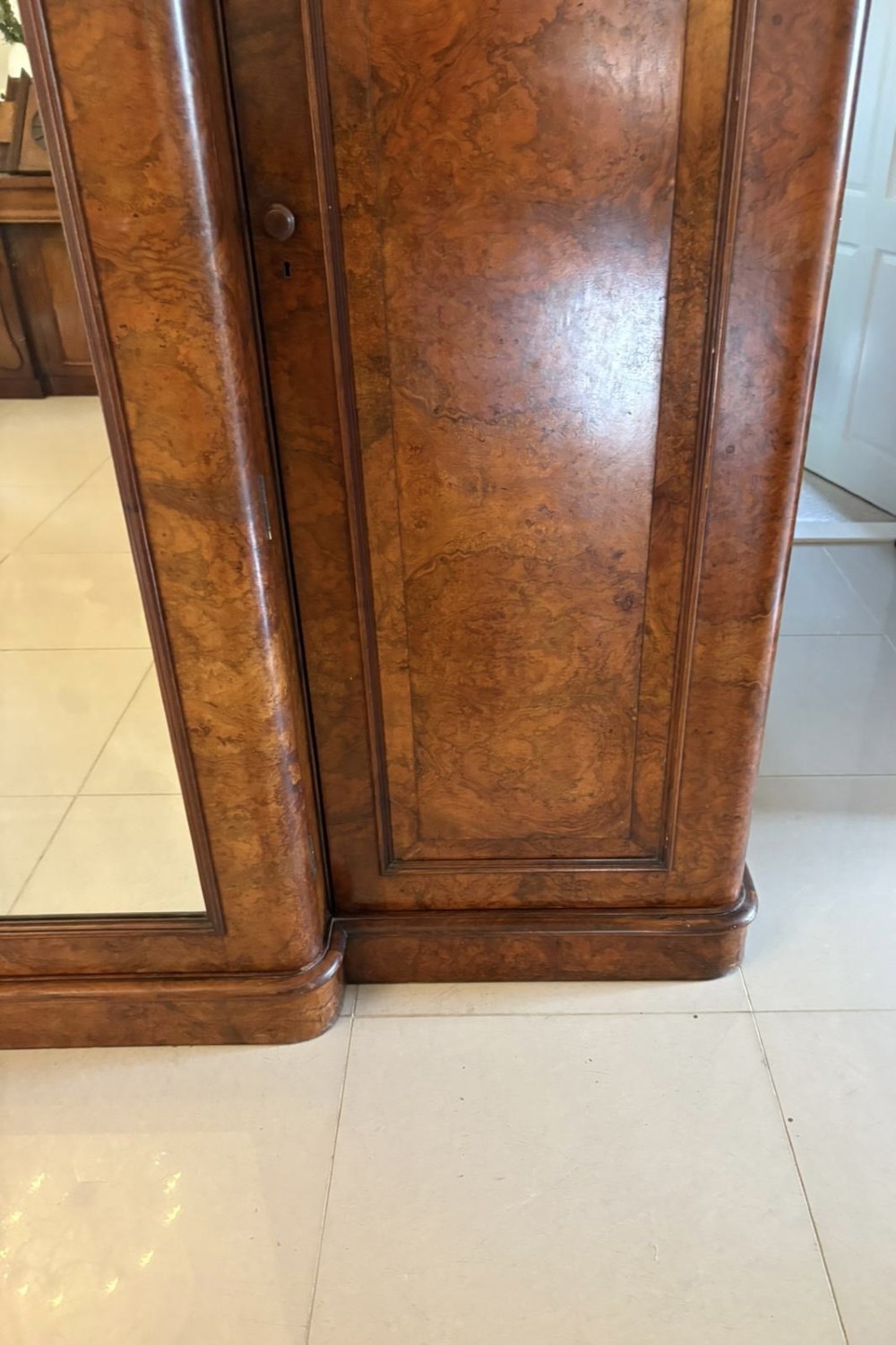 An antique Victorian burr walnut three-door wardrobe featuring an arched central mirrored door crowned with a carved crest, flanked by two burr walnut panelled doors. View VII