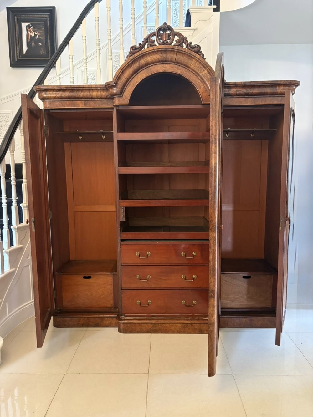 An antique Victorian burr walnut three-door wardrobe featuring an arched central mirrored door crowned with a carved crest, flanked by two burr walnut panelled doors. View X