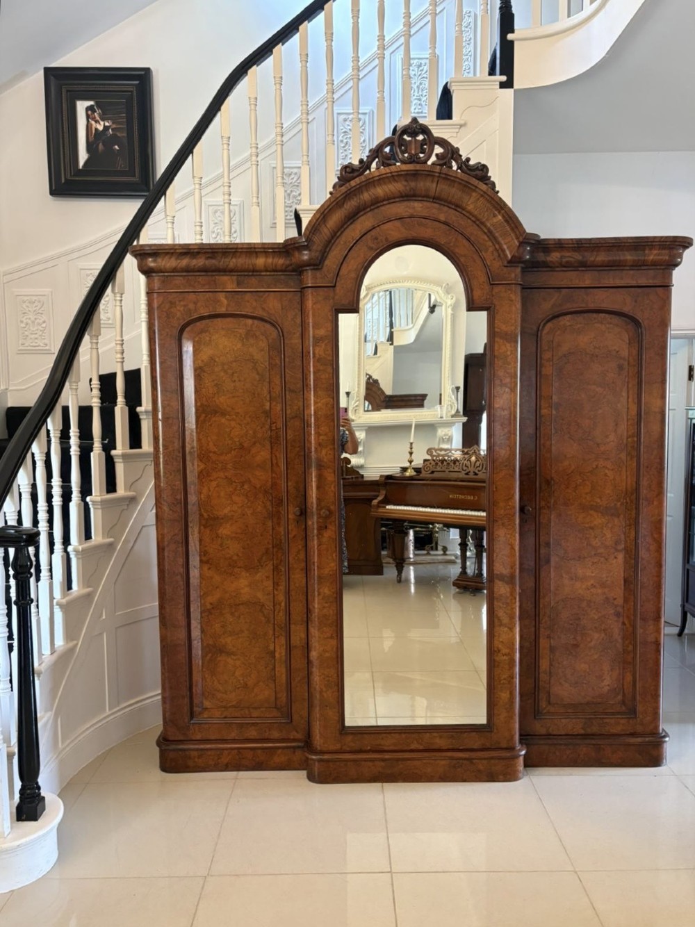 An antique Victorian burr walnut three-door wardrobe featuring an arched central mirrored door crowned with a carved crest, flanked by two burr walnut panelled doors. View XII