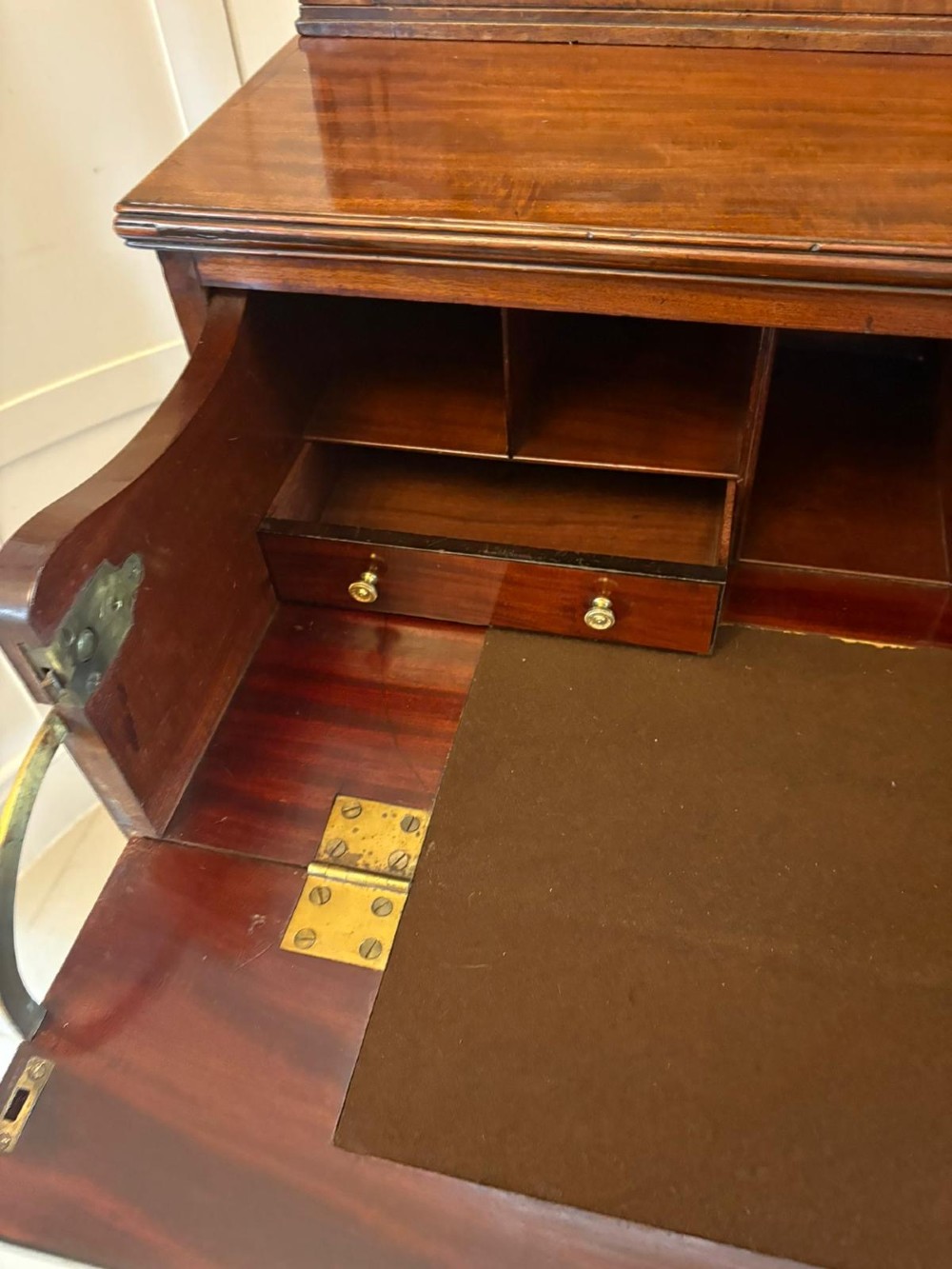 A tall Regency mahogany secretaire bookcase featuring two upper glazed doors with curved glazing bars above a chest of drawers with ornate brass handles. View X
