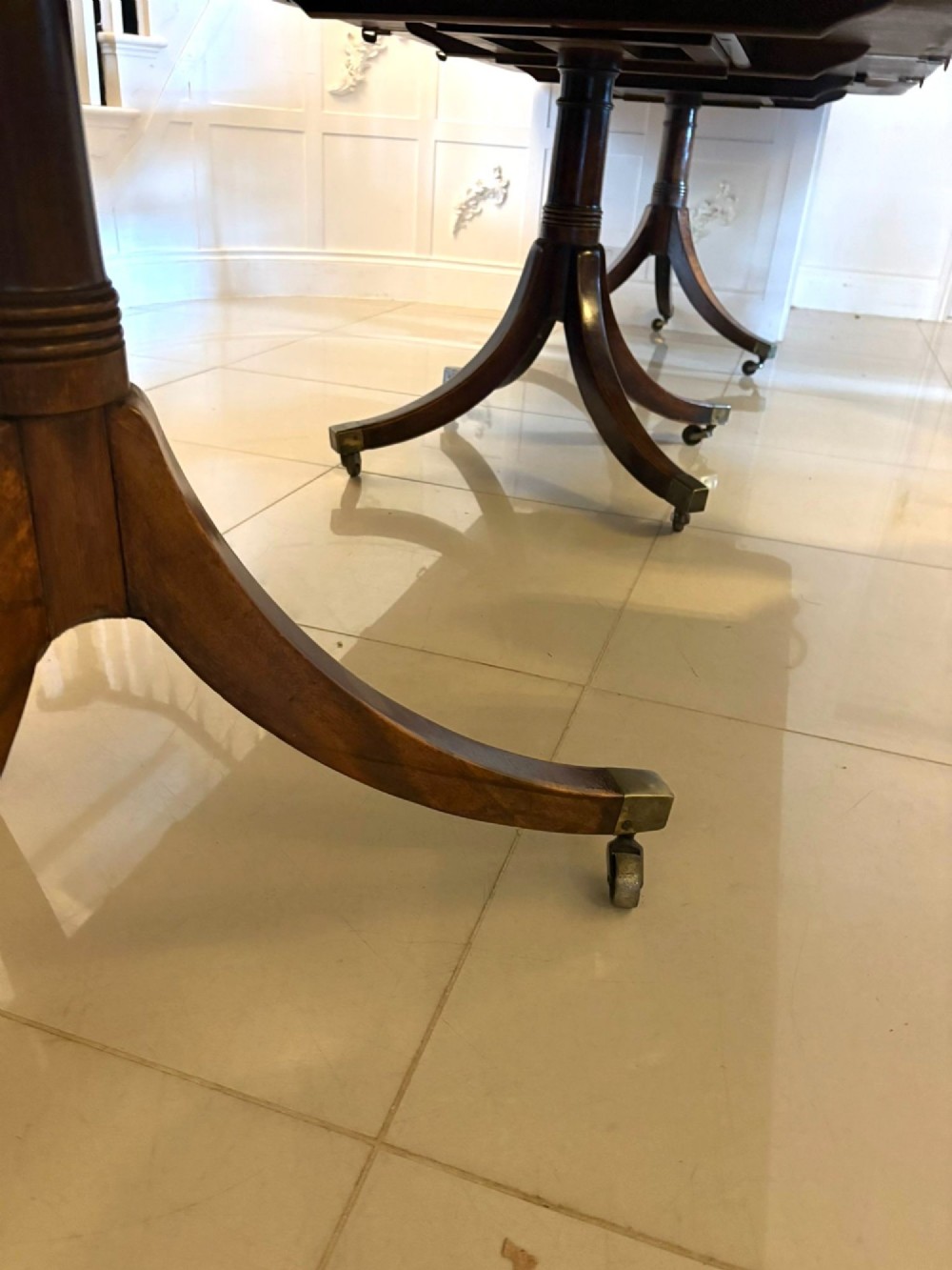 A Regency mahogany extending dining table featuring a three-pillar pedestal base with splayed legs and brass castors. View III