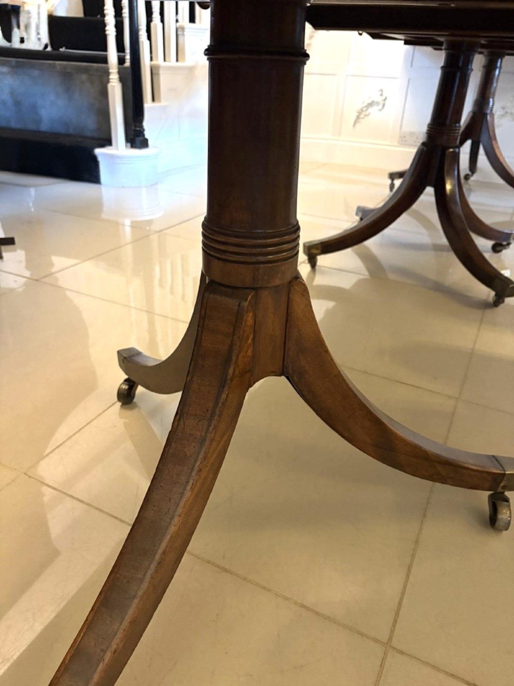 A Regency mahogany extending dining table featuring a three-pillar pedestal base with splayed legs and brass castors. View VIII