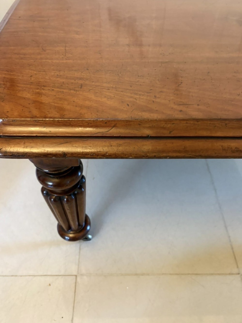 A large Victorian mahogany extending dining table with a polished surface, moulded rim, additional leaves, and turned fluted legs on brass castors. View III