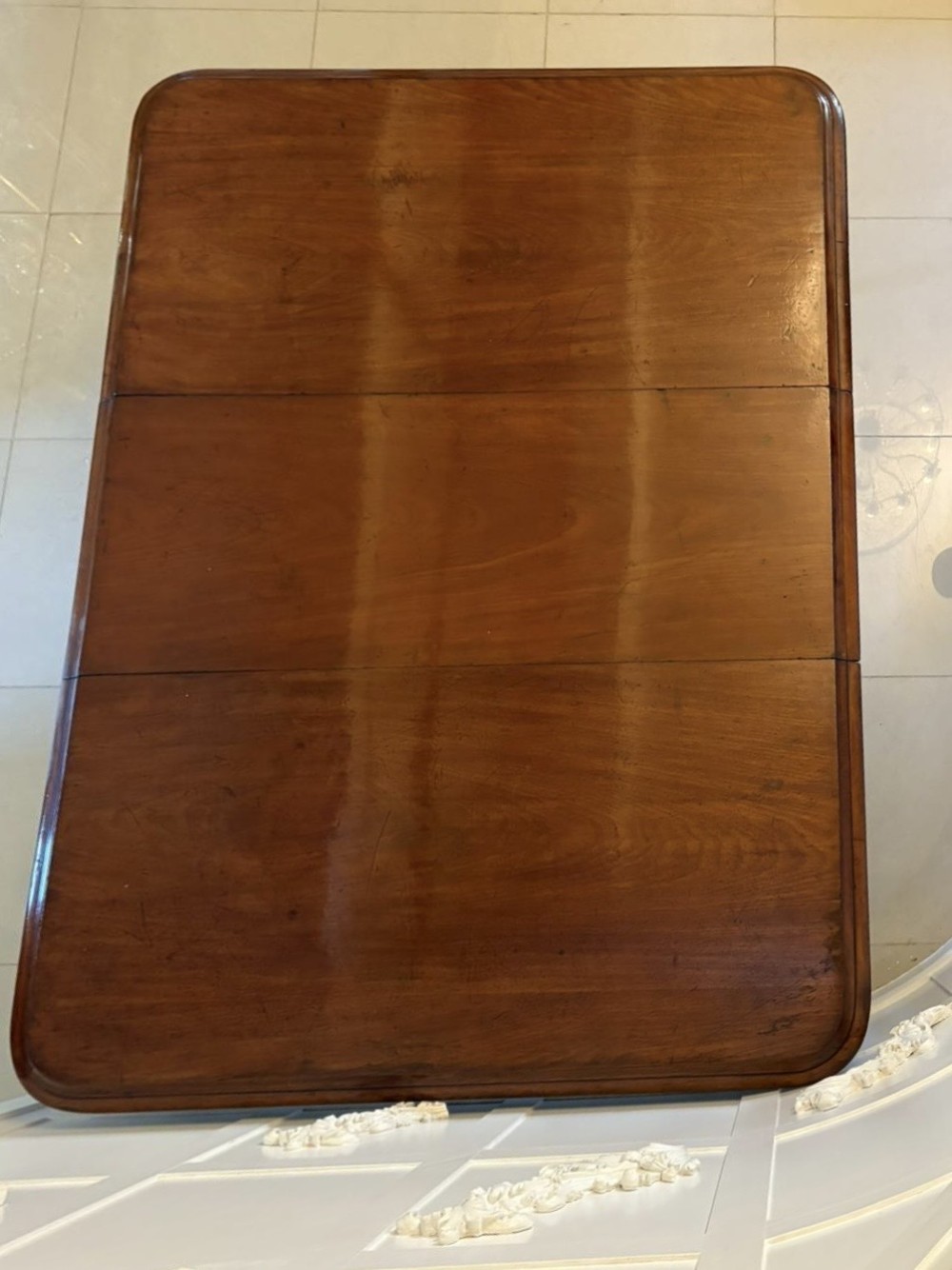 A large Victorian mahogany extending dining table with a polished surface, moulded rim, additional leaves, and turned fluted legs on brass castors. View VI
